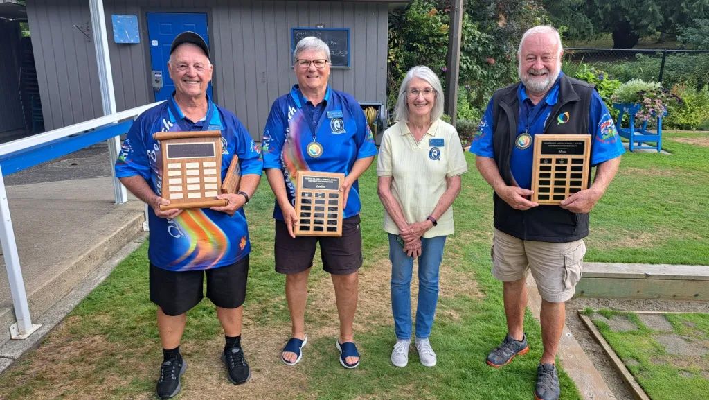 Four members holding up a total of 3 tournament plaques.